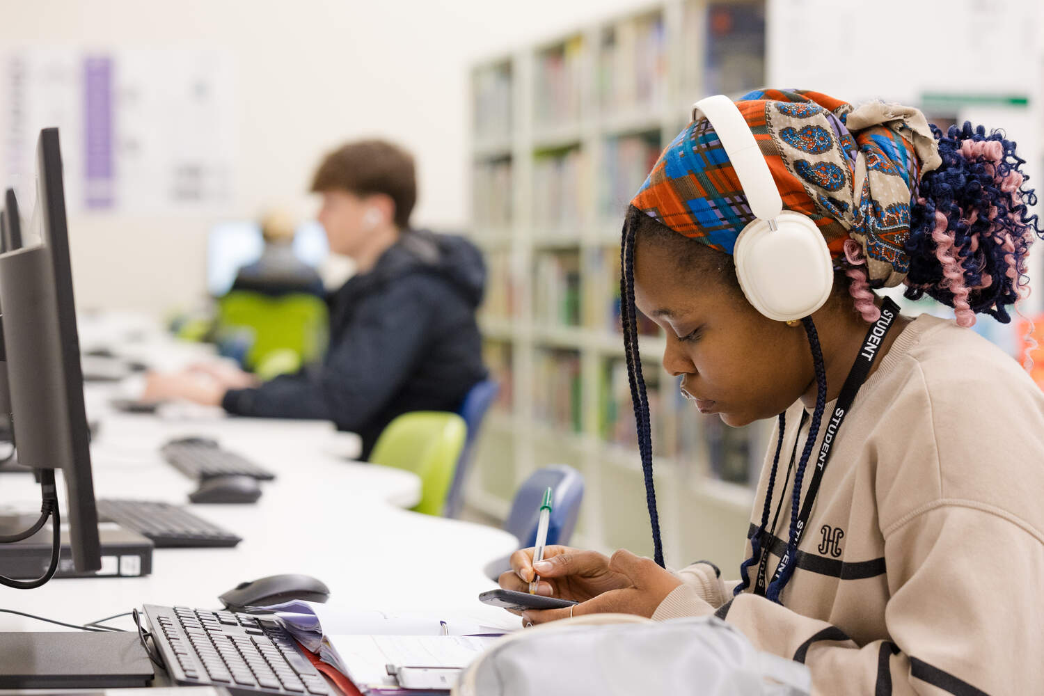 a student alone at a desk studying with her headphones on