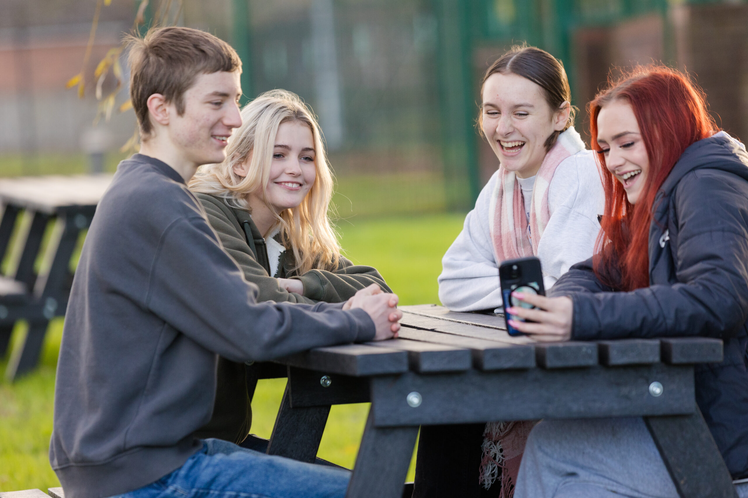 Four students sat outside at a table laughing