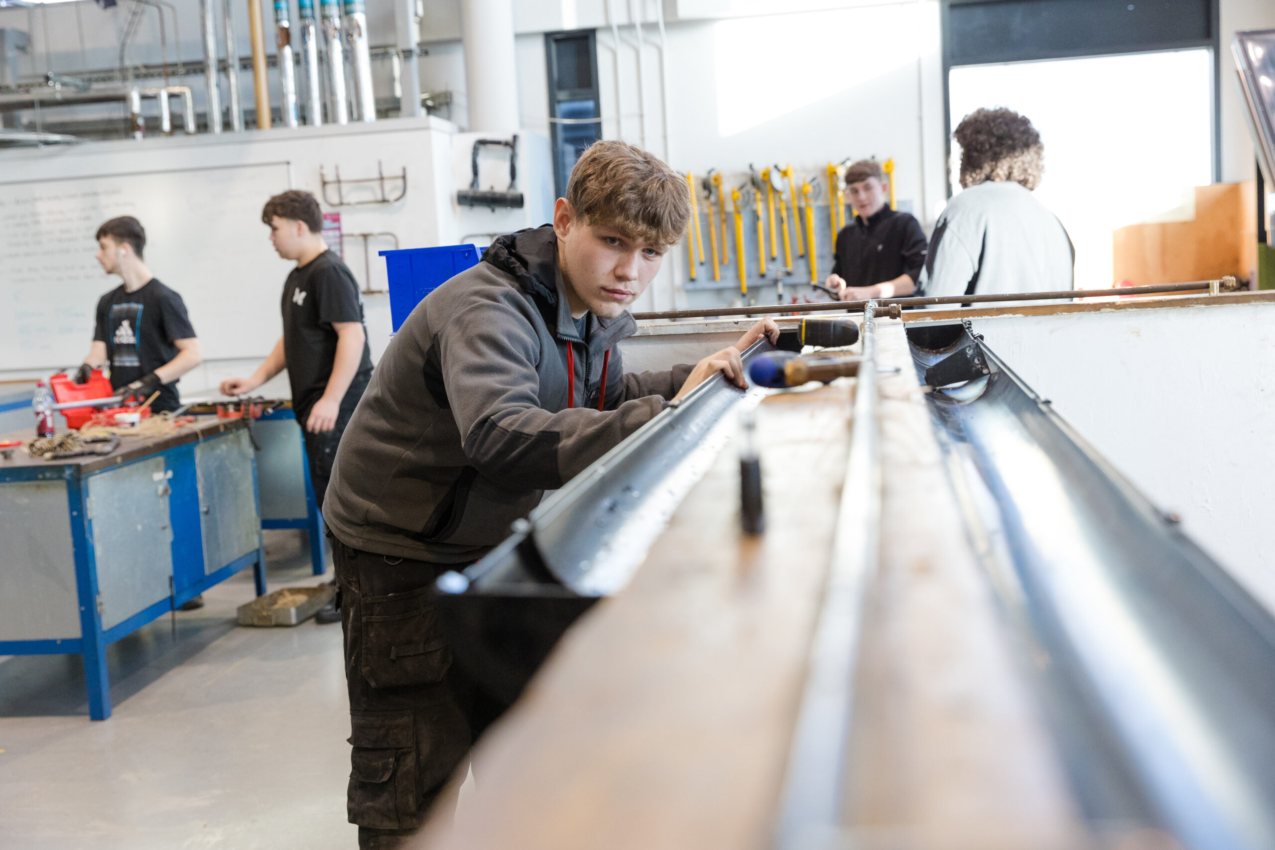 engineering student working with metalwork with students in the background
