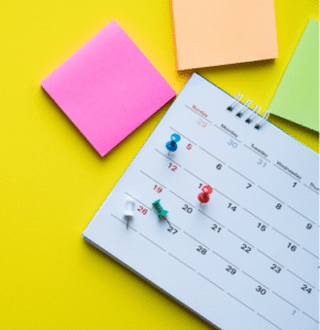 calendar with pins on dates surrounded by post it notes